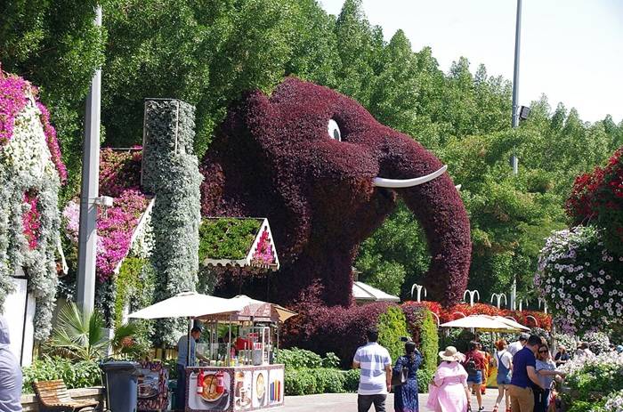 Çiçeklerle süslenmiş devasa bir fil figürü ve çiçeklerle kaplı evler