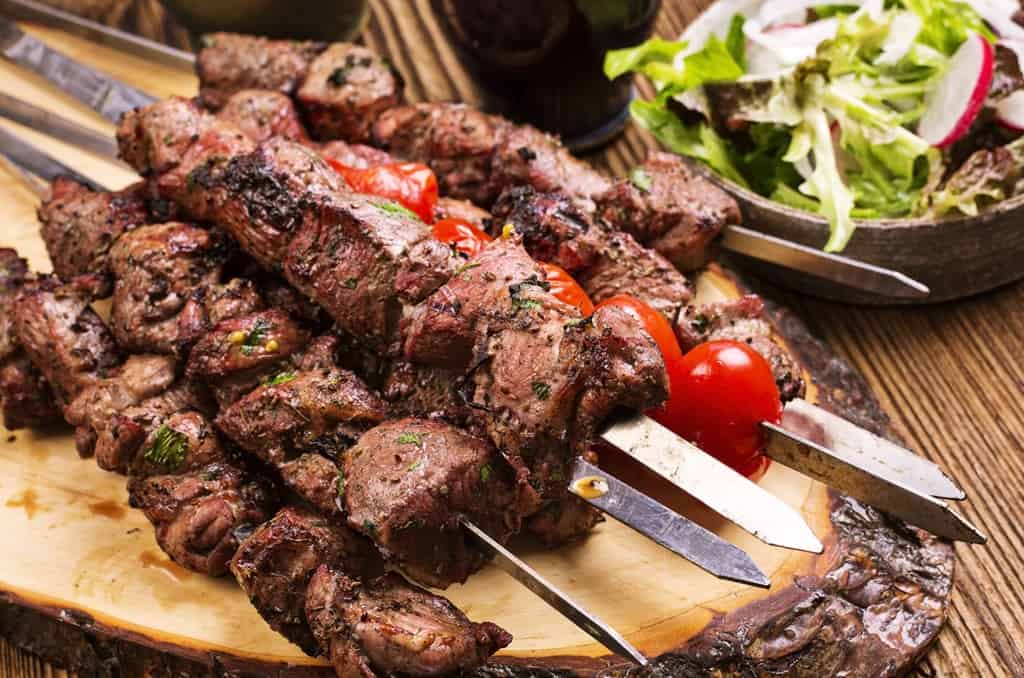 Geleneksel Yunan mutfağından çeşitli lezzetler sunan bir masa düzeni; suvlaki, et şiş